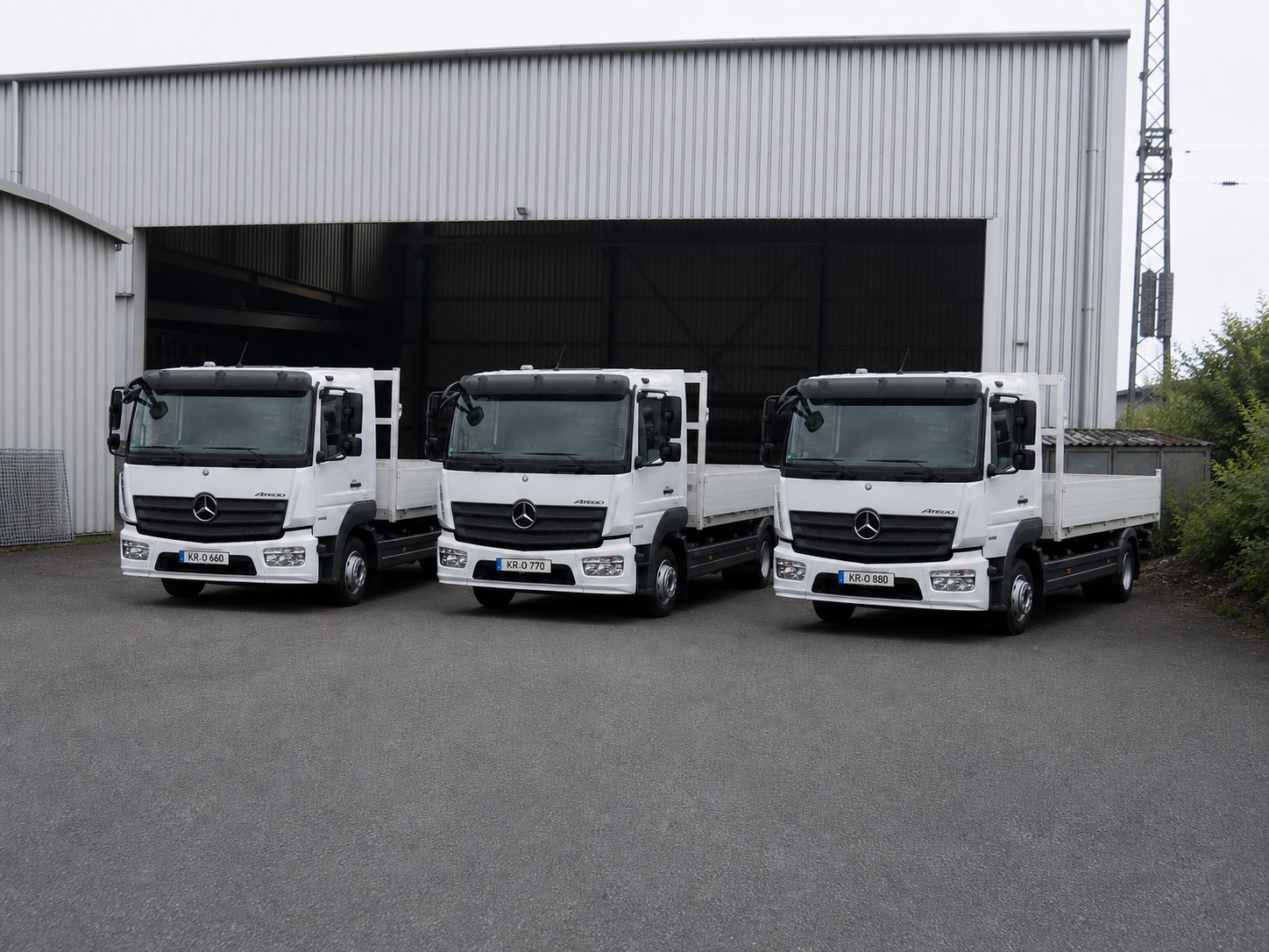Drie witte Mercedes-Benz Atego-vrachtwagens van het Franz Huisgen-wagenpark voor de opslaghal